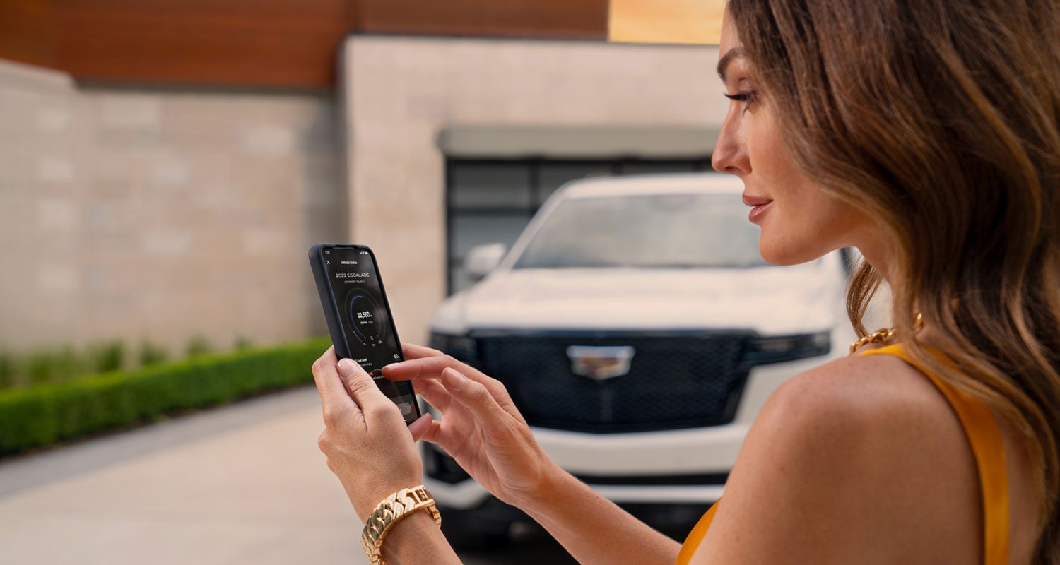lady checking her mobile with a Cadillac vehicle background | Courtesy Cadillac in Louisville KY